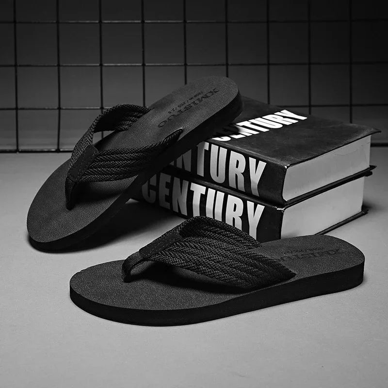 Black woven strap flip flop sandals displayed with stacked 'Century' books in monochrome setting