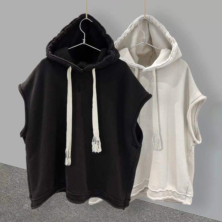 Black and white sleeveless hooded sweatshirts with drawstrings hanging on hangers against gray background