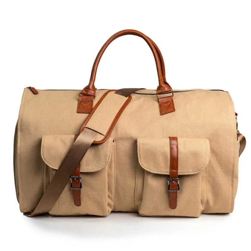Beige canvas duffel bag with brown leather handles, dual front pockets, and adjustable shoulder strap