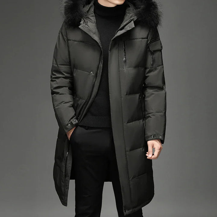 Men's black long padded winter coat with fur hood and zippered pockets, styled over black turtleneck