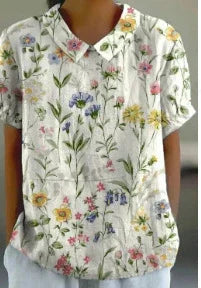 Woman wearing a short-sleeve white shirt with colorful floral print and pockets