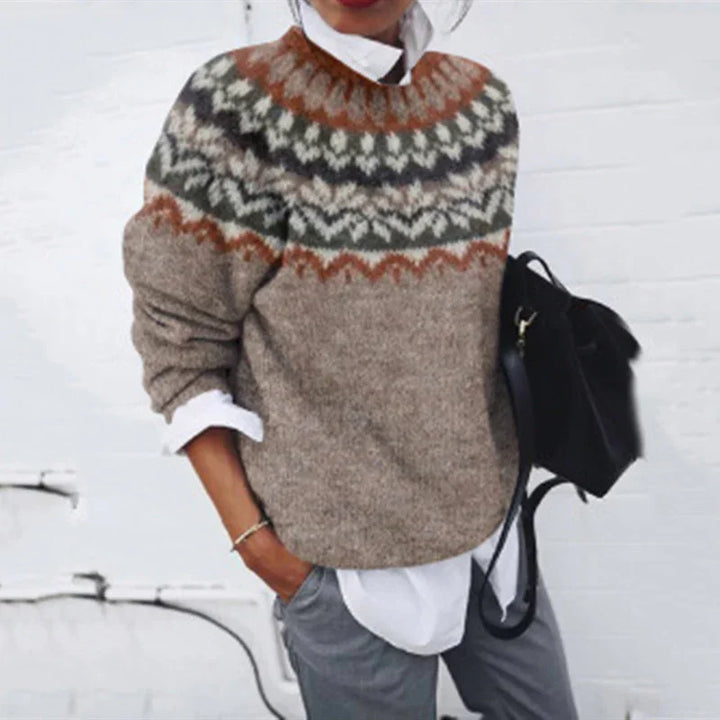 person wearing a cozy patterned knit sweater with earthy tones over a white shirt, carrying a black bag