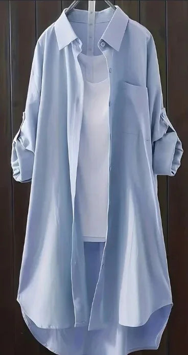Light blue long sleeve shirt dress over white tank top hanging on black background