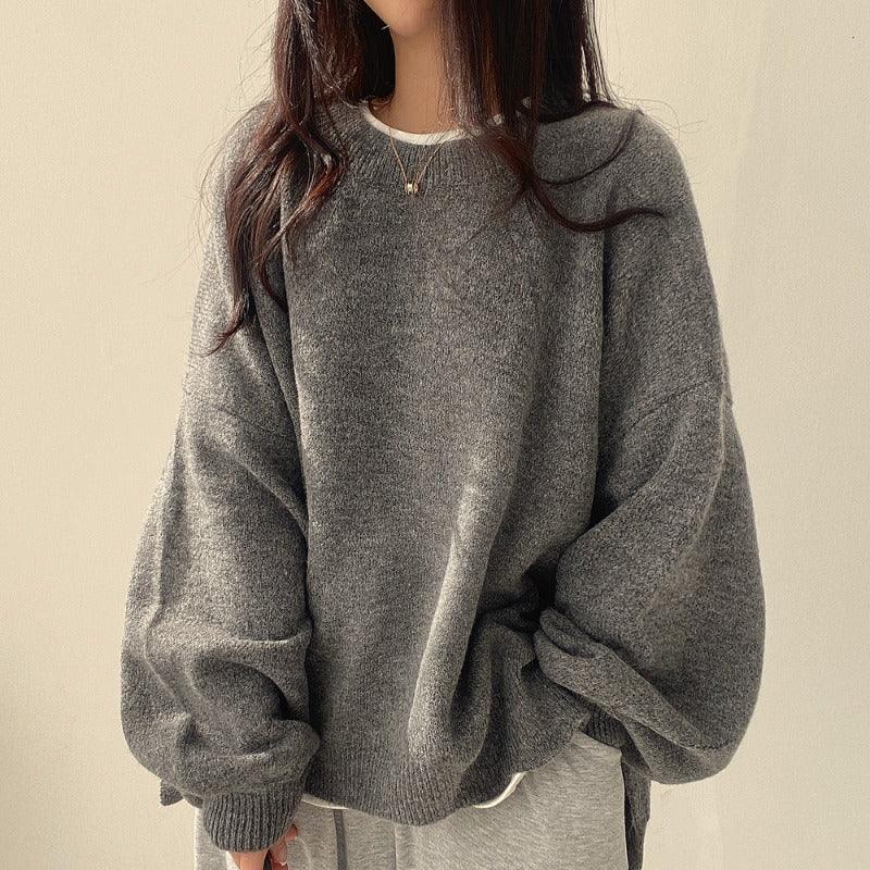 woman wearing oversized grey sweater with balloon sleeves and light grey pants against beige background