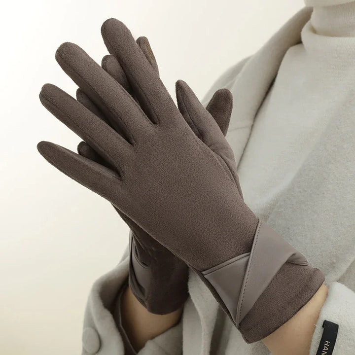 Woman wearing soft brown winter gloves with leather accents, paired with a light beige coat and turtleneck