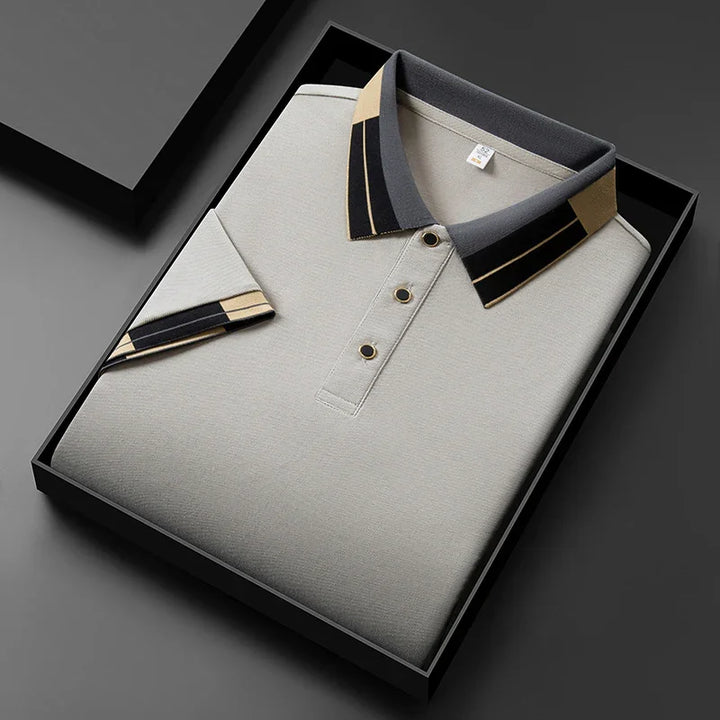 Folded beige polo shirt with black and beige striped collar and sleeve in a black gift box