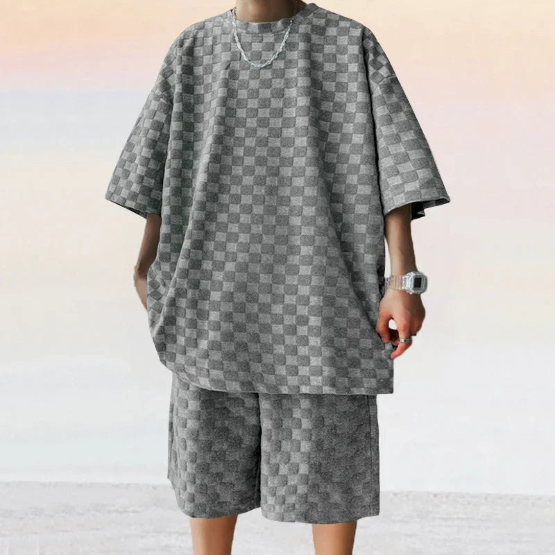 Person wearing oversized gray checkered short-sleeve shirt and matching knee-length shorts
