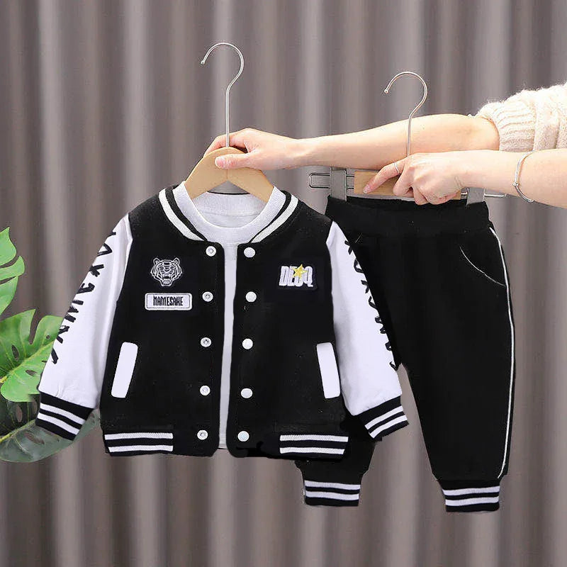 Black and white toddler varsity jacket with patches and matching black pants with white stripes