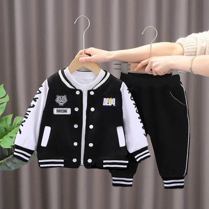 Black and white toddler varsity jacket with patches and matching black pants with white stripes