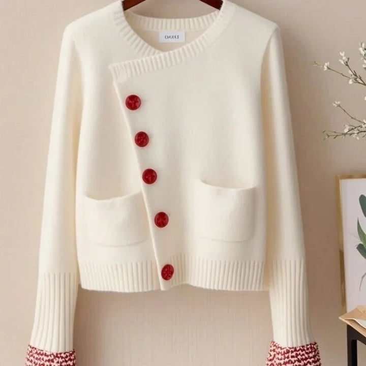 Cream knit cardigan with asymmetric front, red buttons, two front pockets, and ribbed cuffs