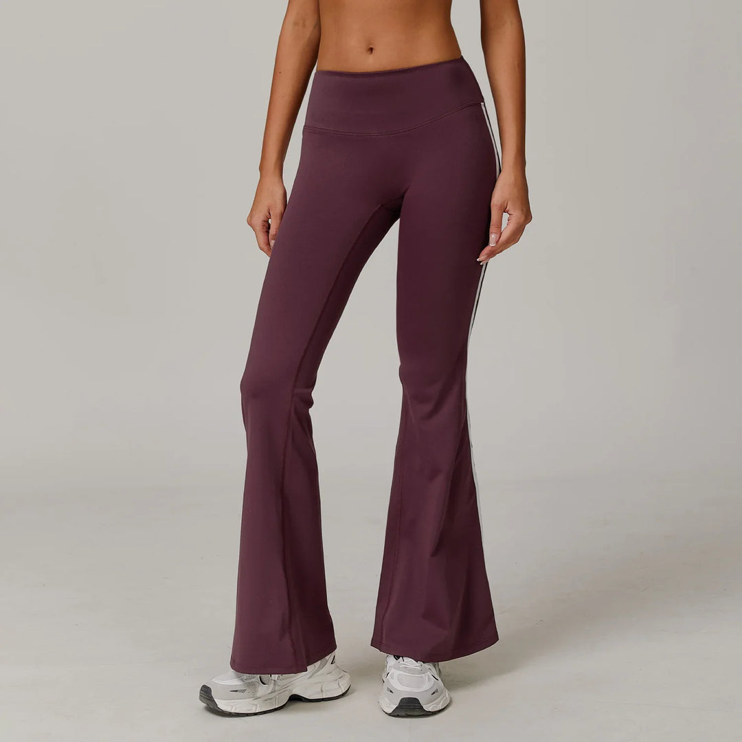 Woman wearing purple high-waisted flare yoga pants with white stripes and white sneakers