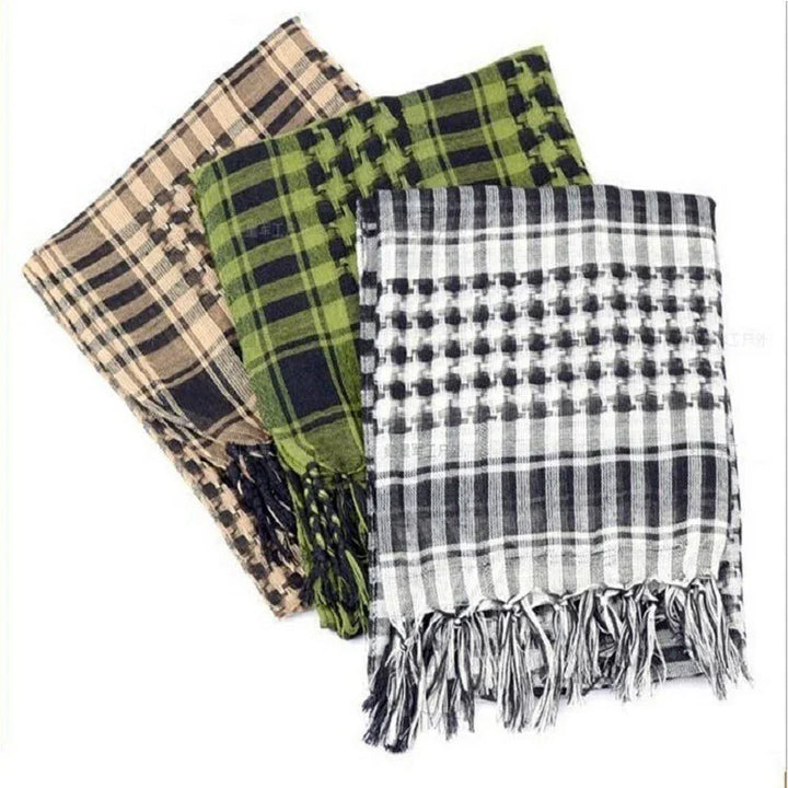 Folded shemagh scarves in black and white, green and black, and tan and black plaid patterns with fringed edges