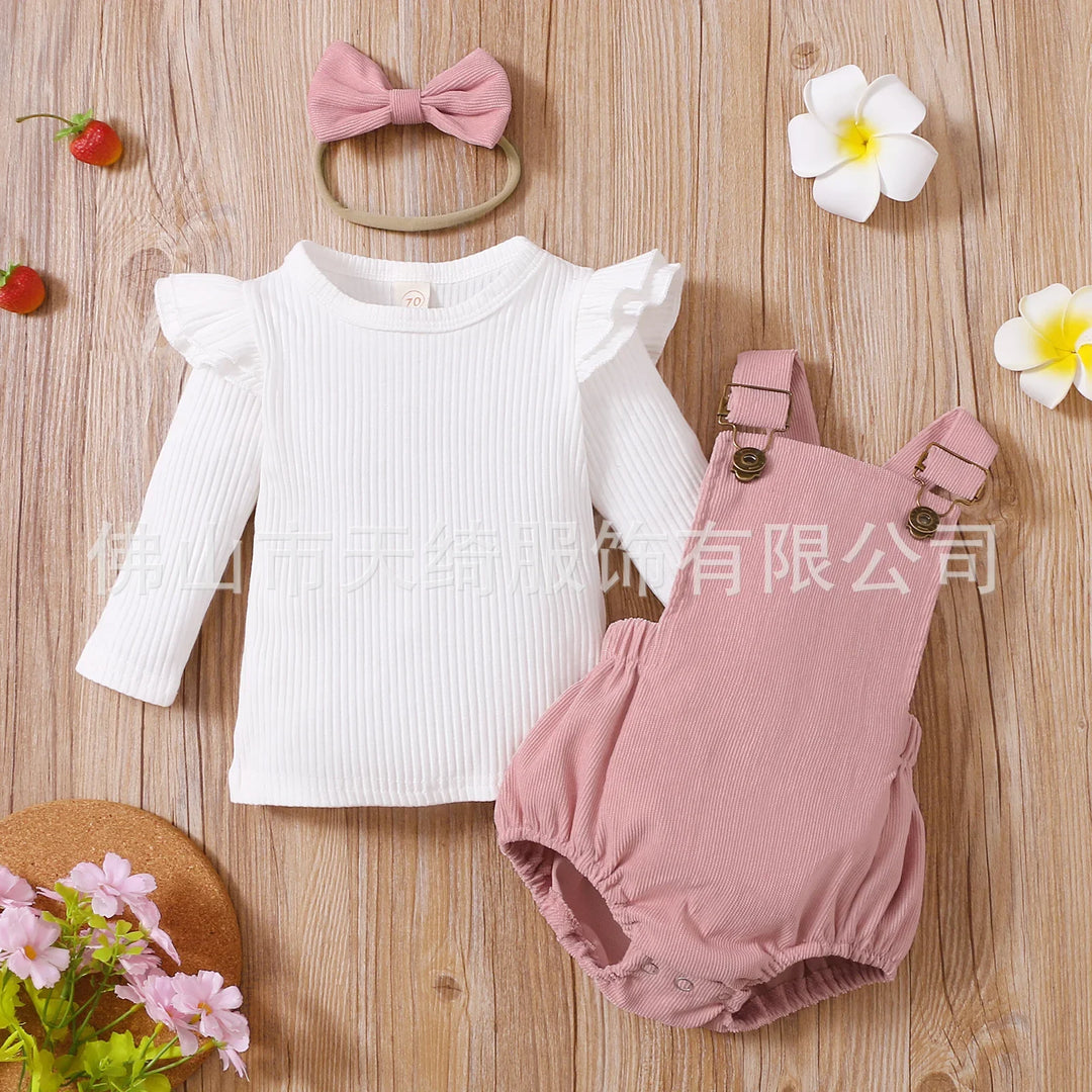 Baby girl's white ruffled long sleeve top with pink romper and pink bow headband on wooden background