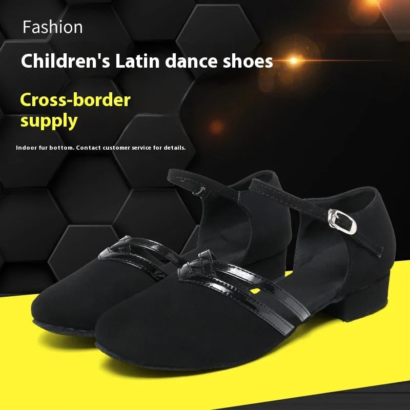 Children's black Latin dance shoes with ankle strap and low heel on yellow and black background