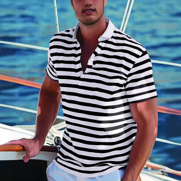 Man wearing black and white striped polo shirt on a boat with ocean background