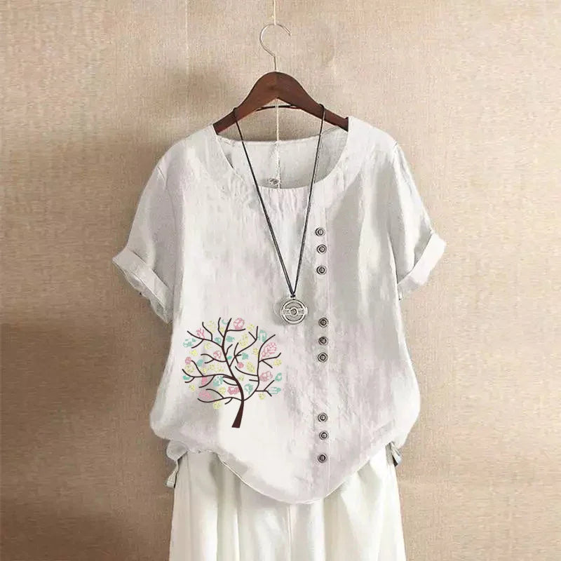 White short-sleeve linen blouse with button details and colorful tree print on left side