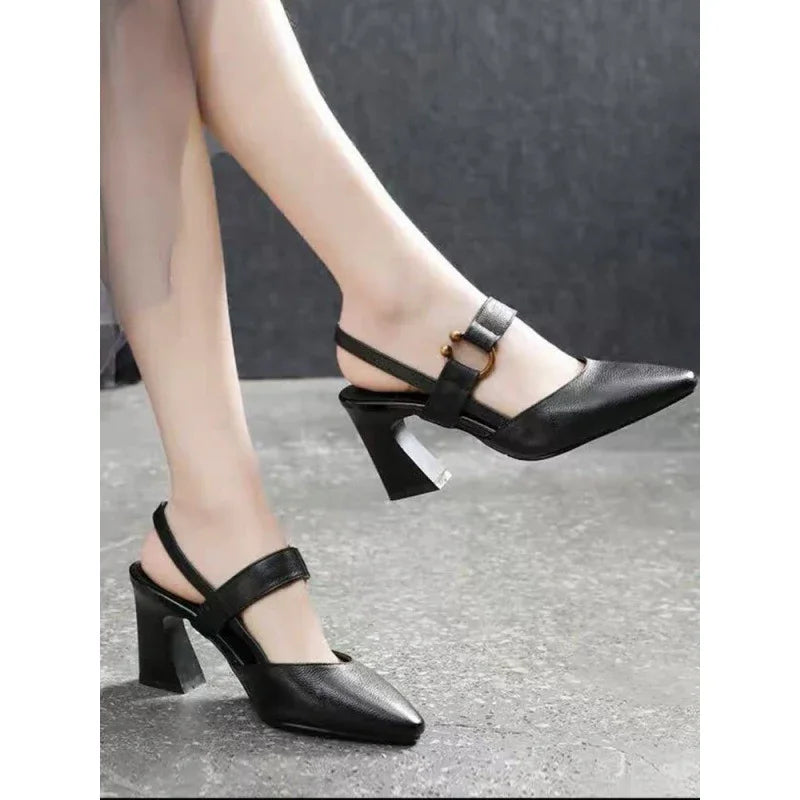 Womens black slingback heels with pointed toe and gold buckle detail on concrete floor
