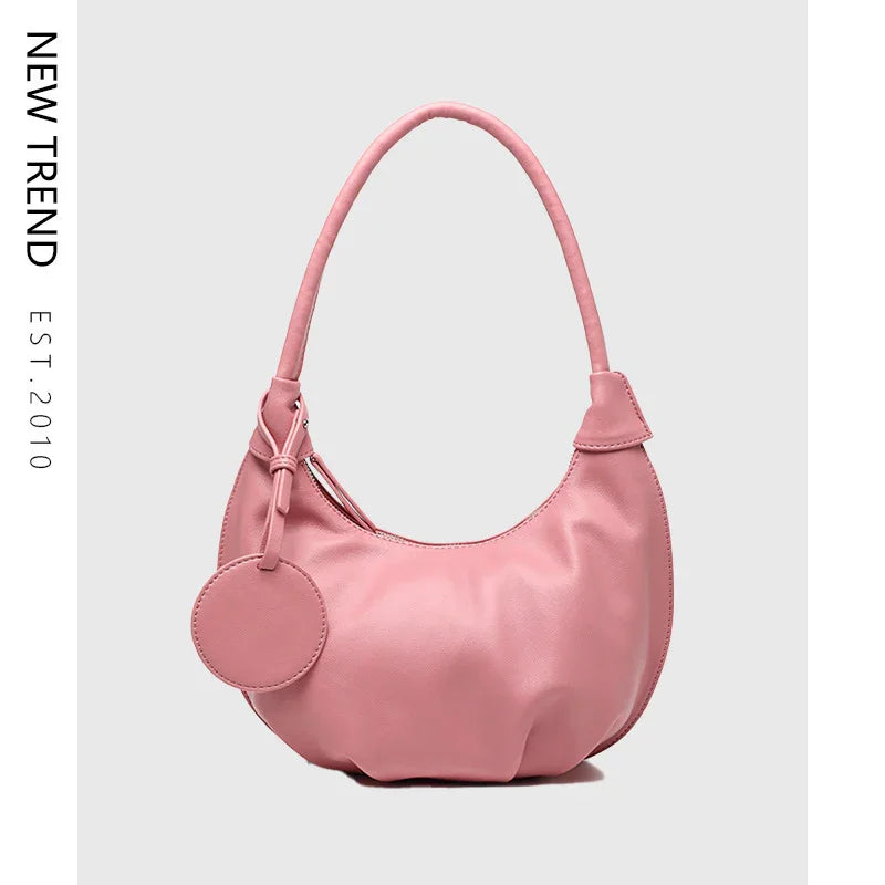 Pink leather shoulder bag with round attached pouch on light gray background