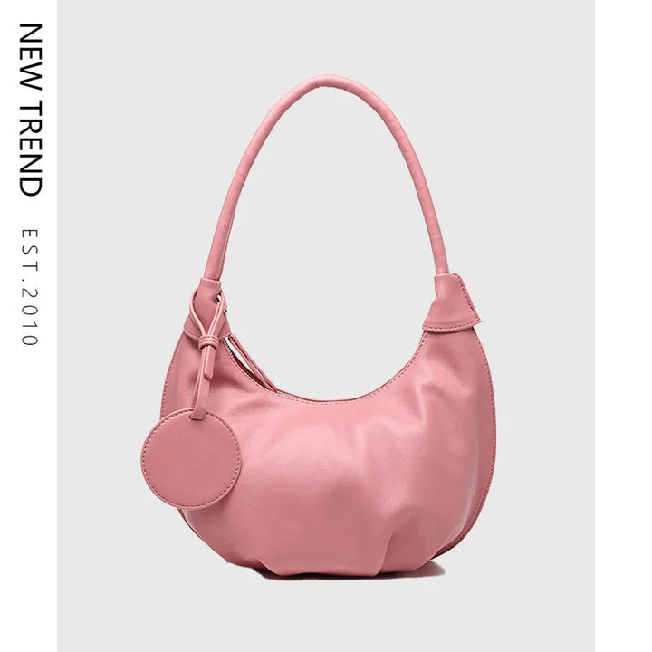 Pink leather shoulder bag with round attached pouch on light gray background