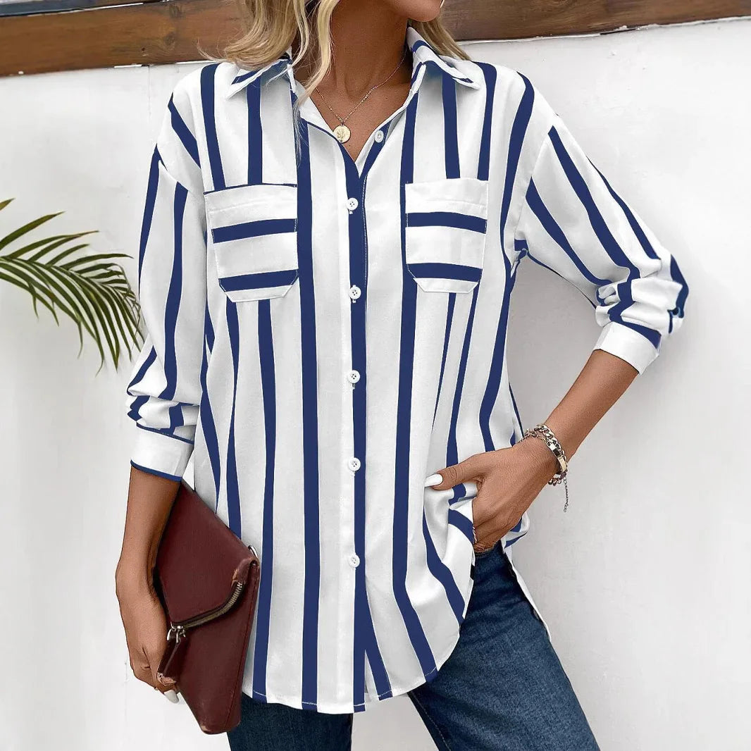 Woman wearing white and navy vertical striped button-up shirt with rolled sleeves, holding brown clutch