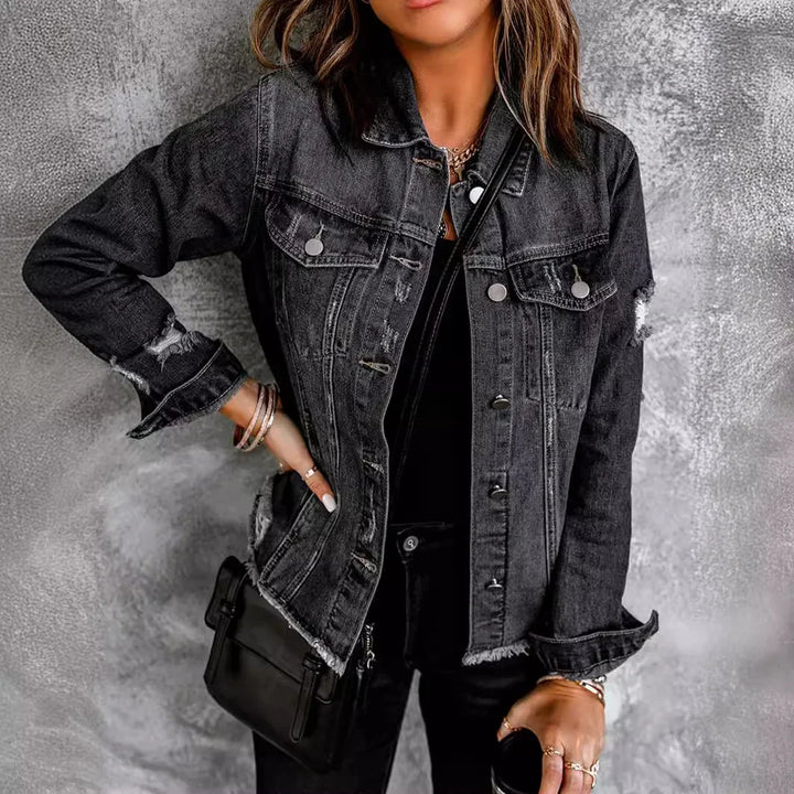 Woman wearing black distressed denim jacket with ripped details and carrying black crossbody bag