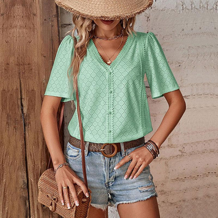 woman wearing mint green eyelet blouse, denim shorts, straw hat, and woven belt with rattan bag