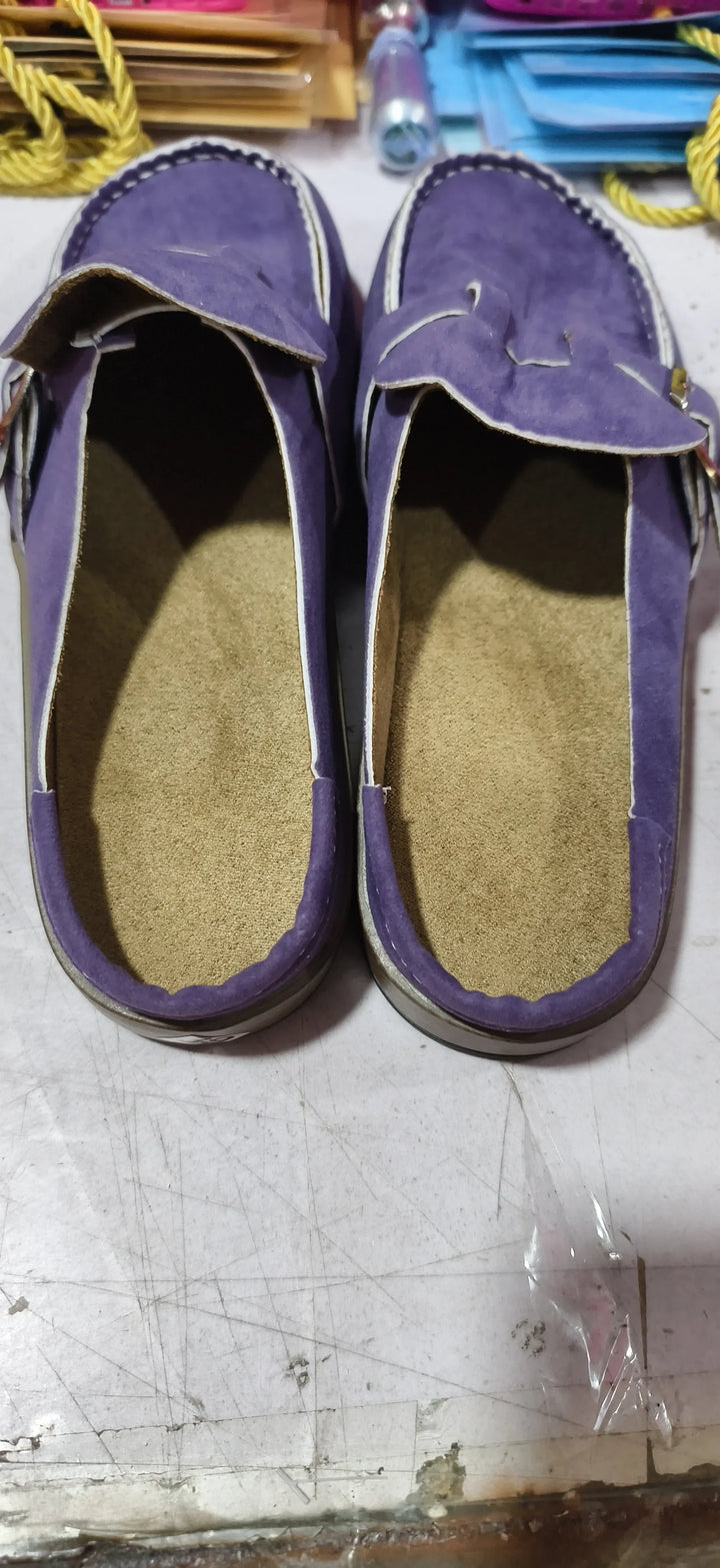 Pair of purple suede loafers with beige insoles on a scratched white surface