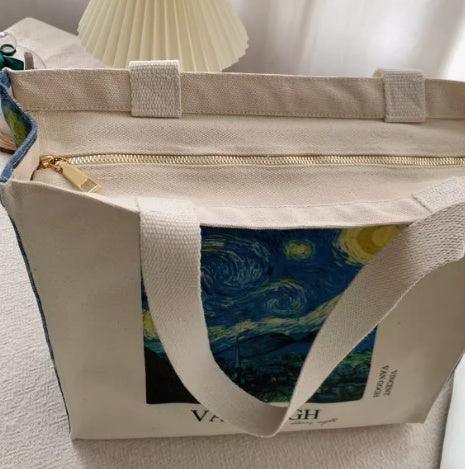 Canvas tote bag featuring Van Gogh's Starry Night print and gold zipper on a white surface