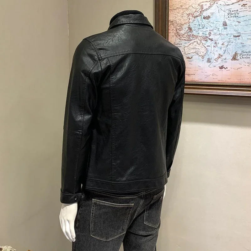 Back view of black leather jacket on mannequin with black jeans near vintage world map