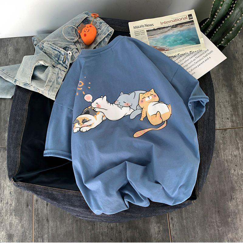 Blue t-shirt with cute cartoon cats lying down, paired with denim jeans and a newspaper on a gray floor