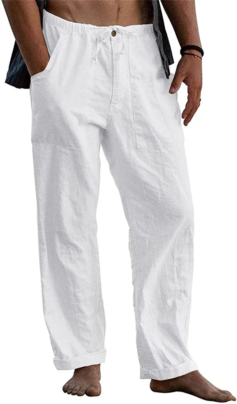 Male model wearing loose white linen pants with drawstring waist and rolled cuffs barefoot