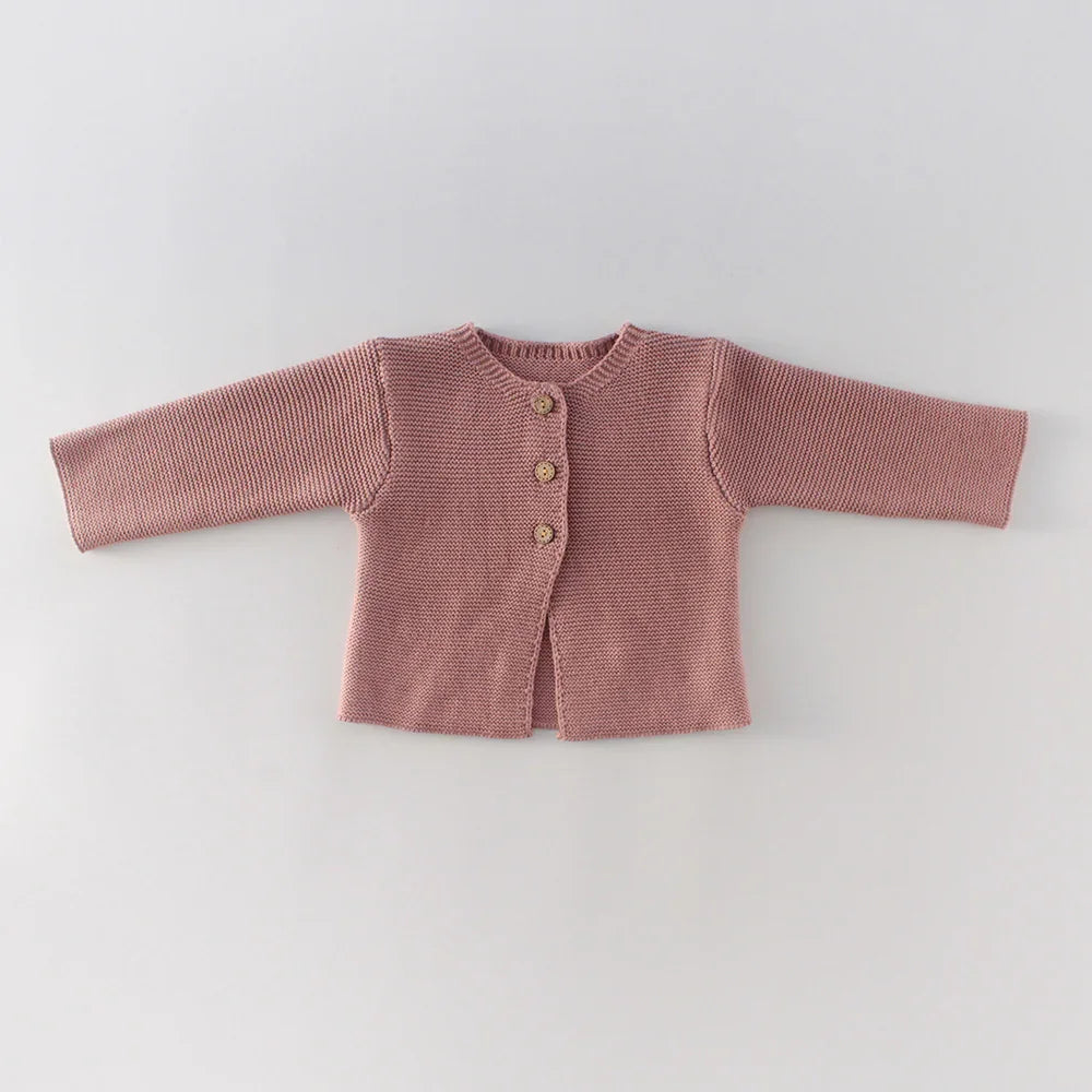 Pink knitted baby cardigan with three wooden buttons on a white background