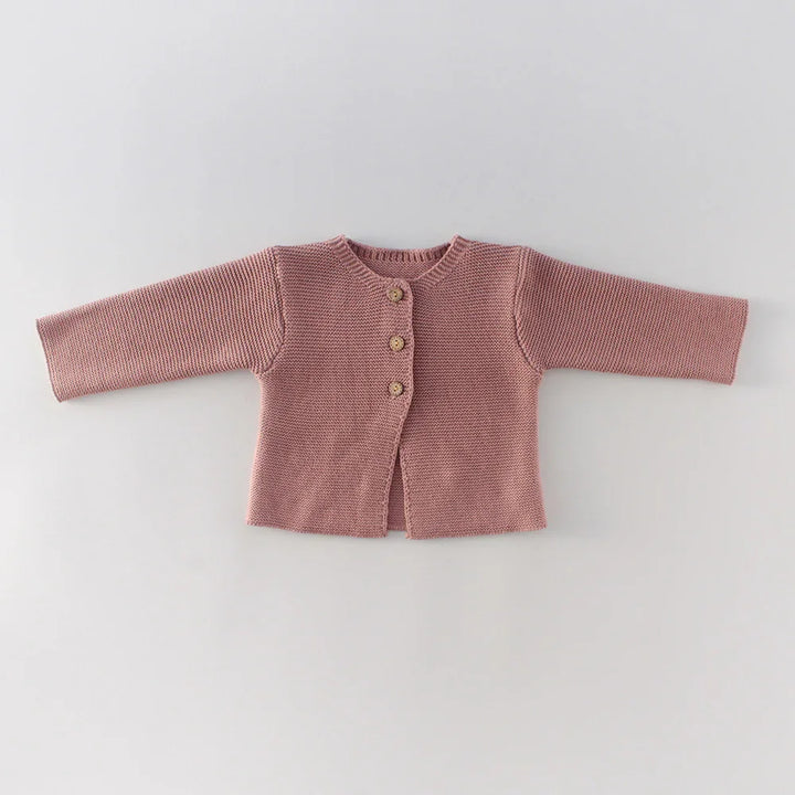 Pink knitted baby cardigan with three wooden buttons on a white background