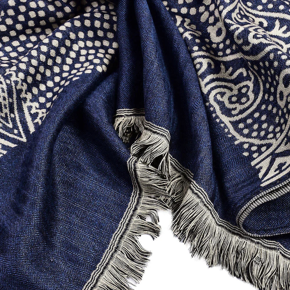 Close-up of navy blue woven fabric with beige geometric and floral patterns and fringed edges