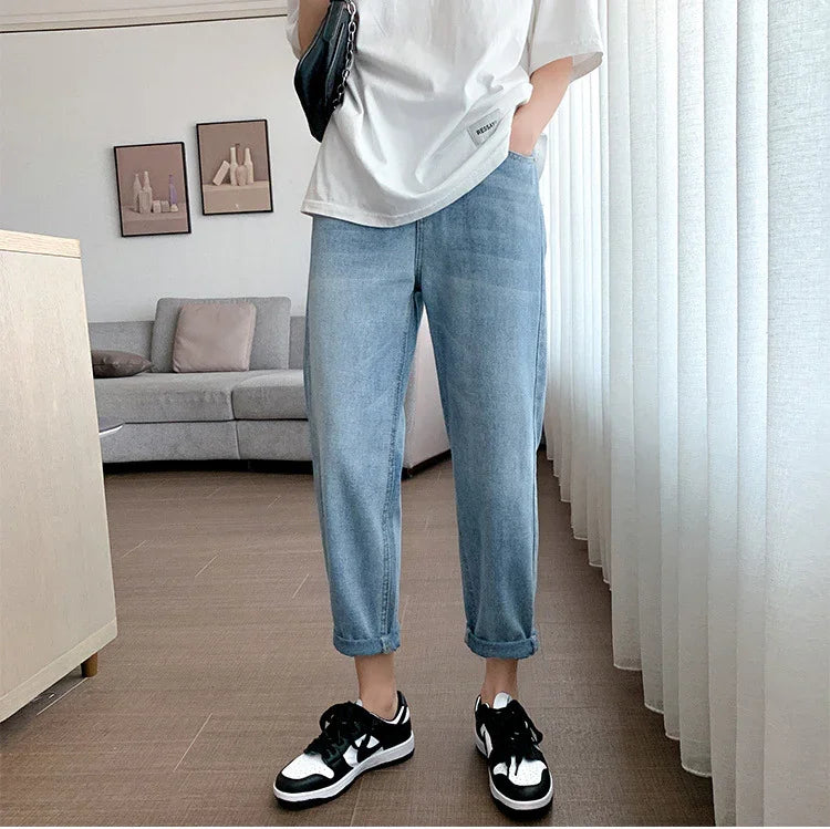 Casual outfit with rolled light blue jeans, white oversized t-shirt, black and white sneakers in modern living room