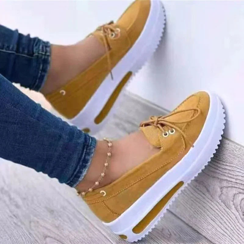 Yellow casual platform shoes with white thick soles worn with blue jeans on wooden floor