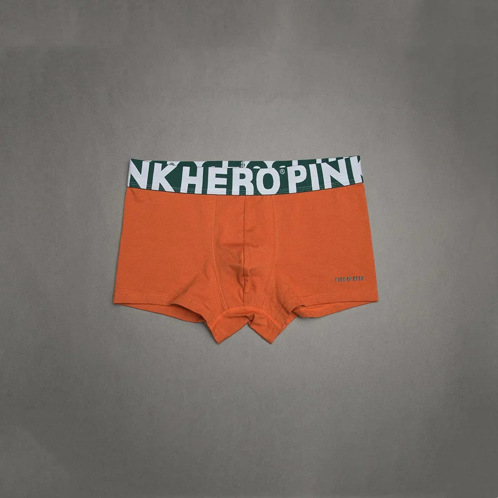 Orange men's boxer briefs with green and white HERO PINK waistband on gray background