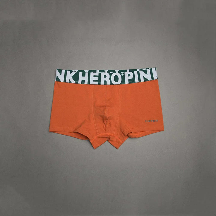 Orange men's boxer briefs with green and white HERO PINK waistband on gray background