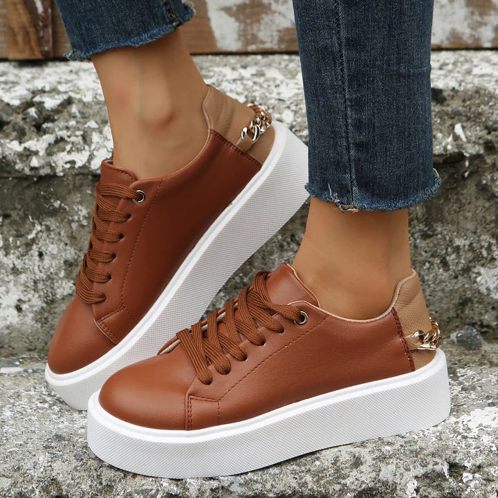 Brown platform sneakers with chain detail worn with frayed hem jeans on stone steps