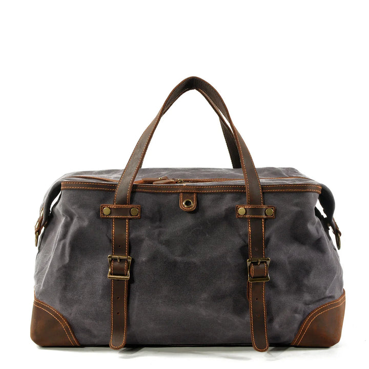Dark gray canvas weekend duffel bag with brown leather handles, straps, and brass buckles