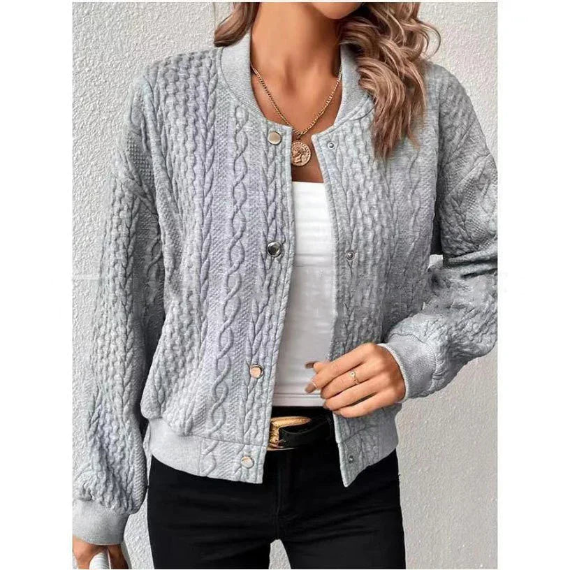 Woman wearing light gray cable knit bomber jacket over white top with black pants and gold necklace