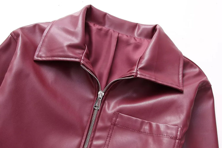 Close-up of maroon faux leather jacket with zipper and collar on white background