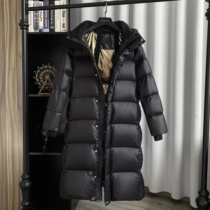 Long black puffer winter coat with shiny shell and gold patterned lining, hanging on rack