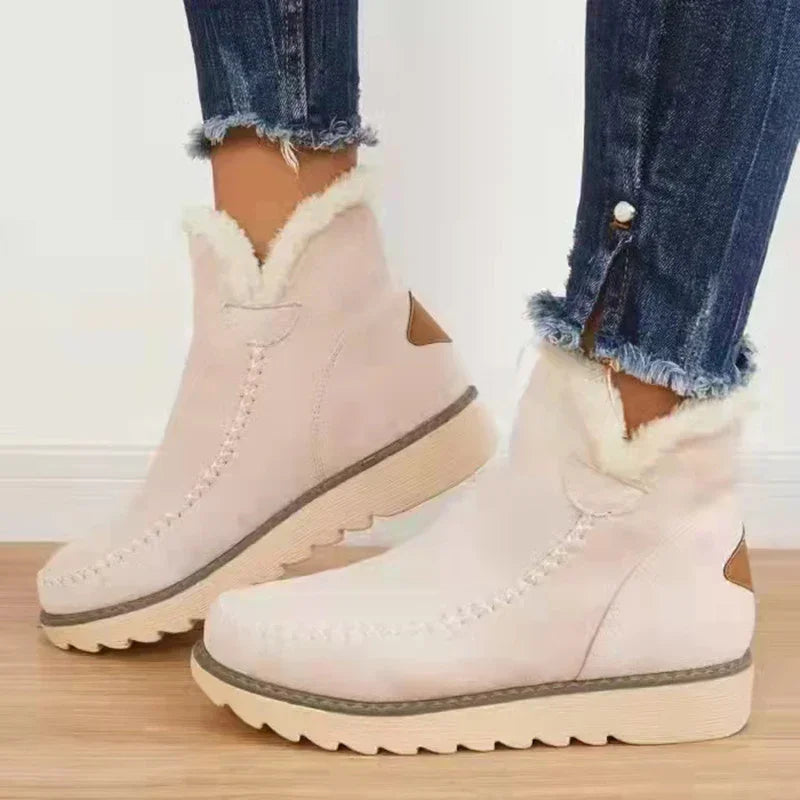 Women wearing white faux fur lined winter ankle boots with beige soles and dark blue cuffed jeans
