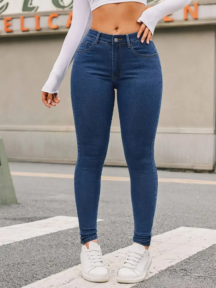 Woman wearing high-waisted blue skinny jeans and white sneakers on urban street
