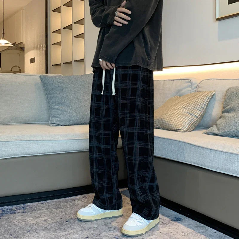 Person wearing black plaid wide-leg pants with white drawstring and white sneakers in modern living room