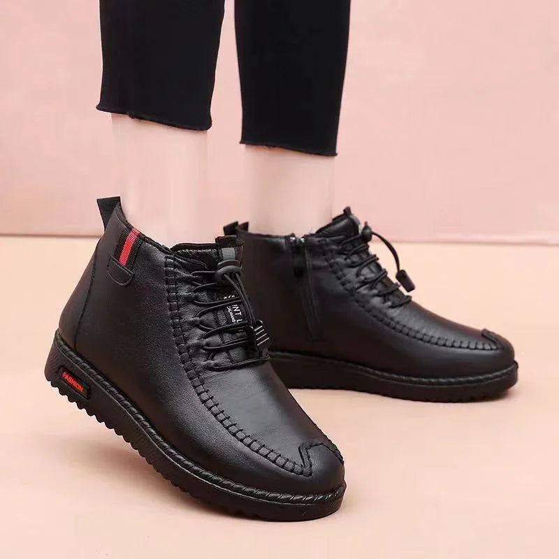 Black leather casual ankle boots with elastic laces and red stripe detail, worn with black pants