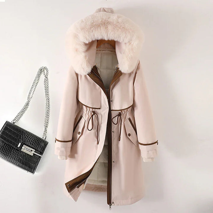 Beige winter coat with faux fur hood and brown trim, paired with black crocodile handbag with silver chain
