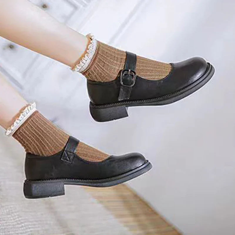 Black Mary Jane shoes paired with brown ribbed socks featuring white lace trim on feet