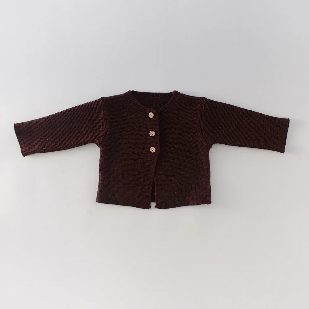 Dark brown knitted baby cardigan with three wooden buttons on a light background